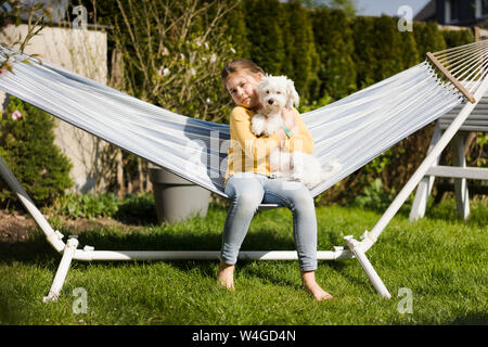 Portrait of Girl with dog in hammock in garden Banque D'Images