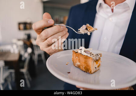 Close-up of businessman ayant un morceau de gâteau dans un café Banque D'Images