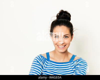 Belle jeune femme avec des cheveux noirs et blanc bleu pullover rayé est posing in front of white background Banque D'Images