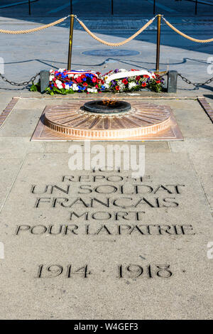 Vue avant de la plaque de granit et flamme éternelle de la Tombe du soldat inconnu située sous la voûte de l'Arc de Triomphe à Paris, France. Banque D'Images