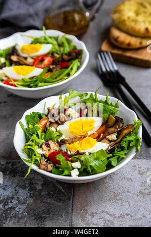 Salade de roquette avec poêlée de champignons, oeuf dur, tomates et feta Banque D'Images