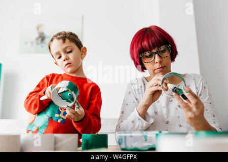 Mère et fils faisant l'artisanat à la maison, la peinture des bobines de carton pour faire un arbre de Noël Banque D'Images