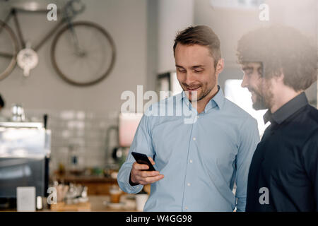 Partenaires d'affaires dans un café d'une réunion, using smartphone Banque D'Images