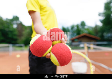 Garçon sur le terrain de tennis, balles de tennis holding Banque D'Images