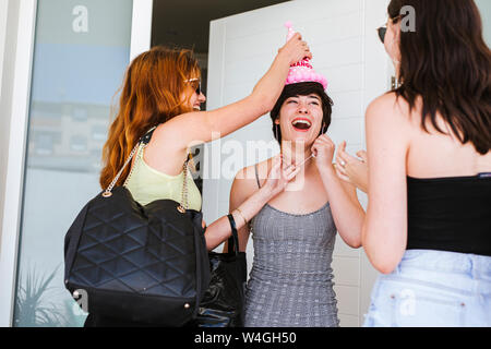 Girlfriends celebrating birthday, surprenant d'amis l'enfant d'anniversaire sur la porte Banque D'Images