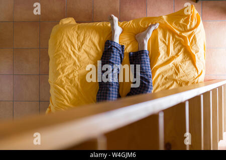Man lying on bed, échelle en bois Banque D'Images
