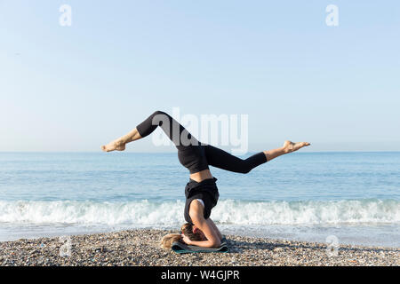 Young woman practicing yoga sur la plage, faire la tête Banque D'Images