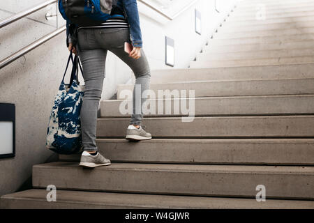 Femme avec sac à dos et en montant un escalier à la station Banque D'Images