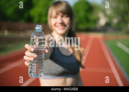 Grande sportive offrant une bouteille d'eau Banque D'Images