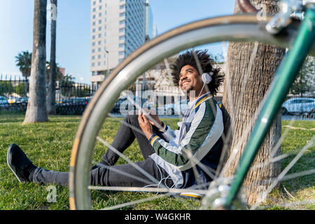 Businessman avec location en faisant une pause dans le parc urbain d'écouter de la musique, Barcelone, Espagne Banque D'Images