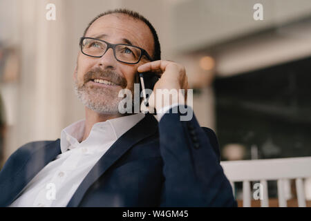 Portrait of mature businessman on cell phone in a cafe Banque D'Images