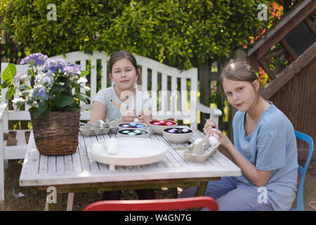 Portrait de deux jeunes filles à la teinture des oeufs de Pâques sur table de jardin Banque D'Images