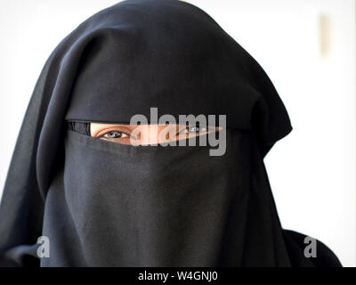 Jeune Indien Muslima avec yeux souriants couvre le reste de son visage avec un voile noir (niqab). Banque D'Images