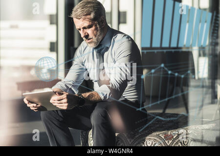 Mature businessman using tablet entouré par des données Banque D'Images