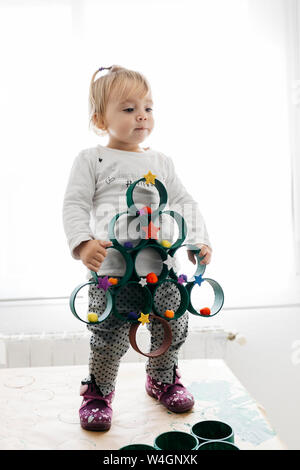 Petite fille avec un arbre de Noël avec des rouleaux en carton peint et accessoires Banque D'Images