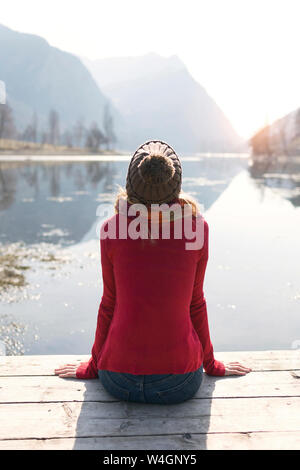 Young blonde woman sitting on jetty à un lac en hiver Banque D'Images