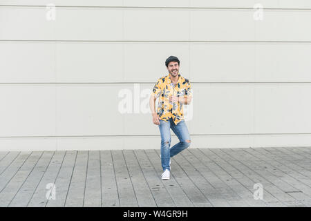 Jeune homme portant chapeau plat et aloha shirt, s'amuser Banque D'Images