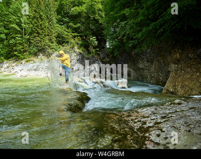 Autriche, Tyrol, Brandenberg, man crossing Brandenberger Ache, splash Banque D'Images