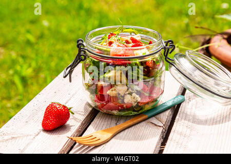 Salade d'avocat aux fraises, la roquette et les pignons de pin dans le jar Banque D'Images