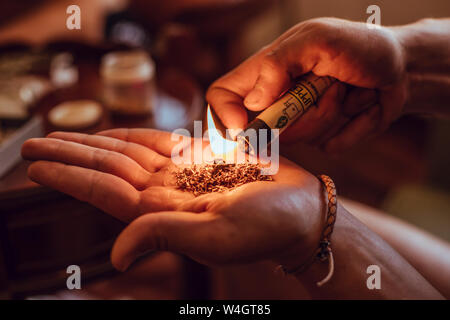 Close-up of mains brûler le tabac et le hachisch avec un briquet Banque D'Images