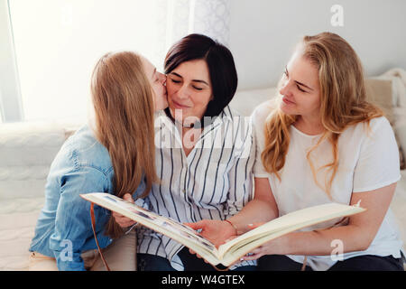 Grandi filles visiter leur mère, en regardant l'album photo Banque D'Images