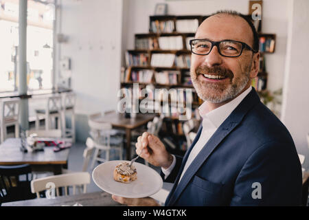 Smiling mature businessman having un morceau de gâteau dans un café Banque D'Images