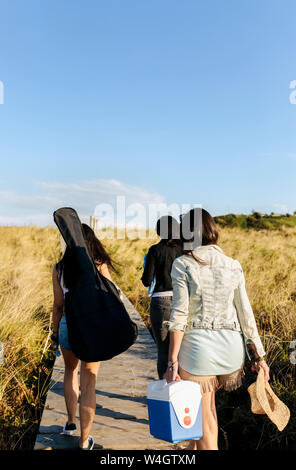 Vue arrière de la femme avec sac de guitare en marche vers les dunes beach Banque D'Images