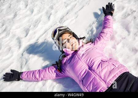 Femme heureuse de prendre une pause après le ski allongé sur le sol enneigé en Sierra Nevada, Andalousie, Espagne Banque D'Images