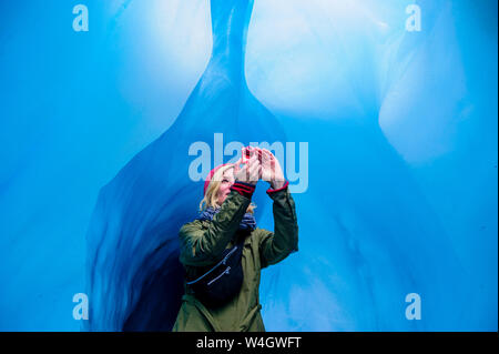 Femme de prendre une photo dans une grotte de glace, Fox Glacier, île du Sud, Nouvelle-Zélande