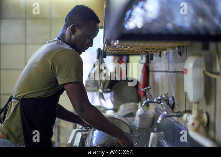 Jeune homme lave-vaisselle dans une cuisine de restaurant, Afrique du Sud Banque D'Images