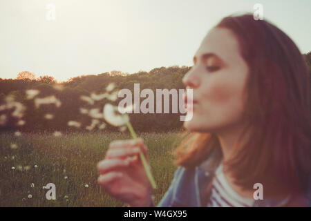 Portrait of teenage girl blowing blowball Banque D'Images