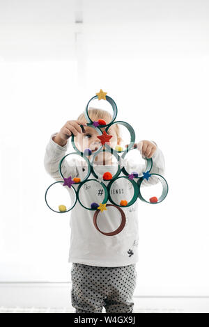 Petite fille avec un arbre de Noël avec des rouleaux en carton peint et accessoires Banque D'Images