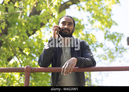 Portrait de jeune homme barbu sur le téléphone à l'extérieur Banque D'Images