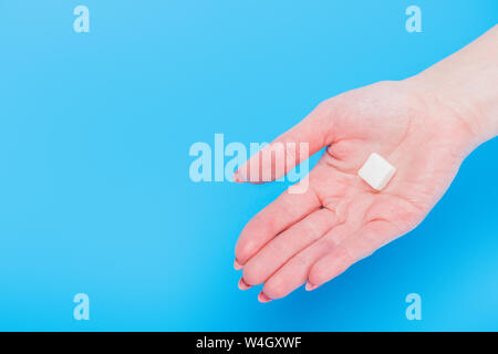 Main de femme Vue de dessus avec le sucre blanc cube sur fond bleu Banque D'Images