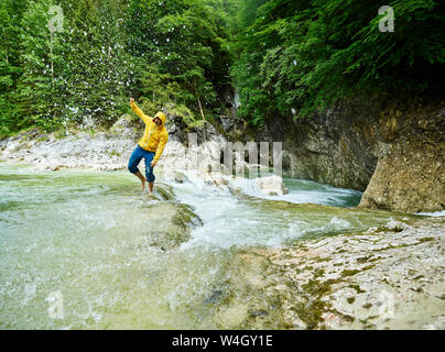 Autriche, Tyrol, Brandenberg, man crossing Brandenberger Ache, splash Banque D'Images