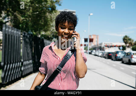 Femme parlant au téléphone tout en marchant dans la ville Banque D'Images