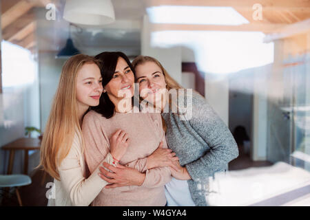 Visiter filles embrassant leur mère, debout à la fenêtre Banque D'Images