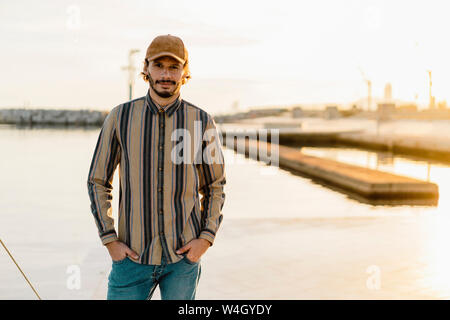 Portrait d'homme portant casquette et chemise rayée au coucher du soleil Banque D'Images