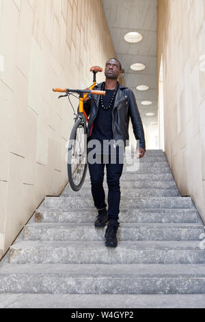 Homme portant son vélo Banque D'Images