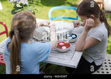 Deux filles de la teinture les oeufs de Pâques sur table de jardin Banque D'Images
