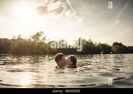 Affectionate couple nageant ensemble dans un lac Banque D'Images