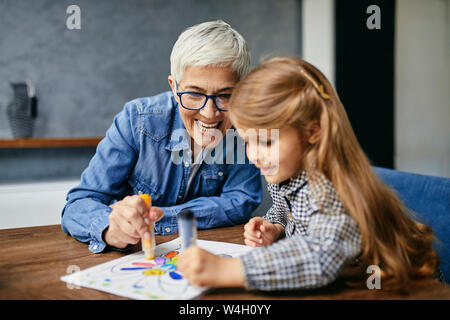 Grand-mère et petite-fille assis à table, livre de coloriage peinture Banque D'Images