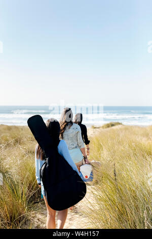 Vue arrière de la femme avec sac de guitare en marche vers les dunes beach Banque D'Images