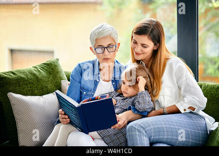 Mère, fille et petite-fille assise sur la table, la lecture d'un livre Banque D'Images