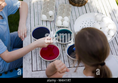Deux filles de la teinture les oeufs de Pâques sur table de jardin Banque D'Images