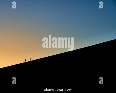 Silhouette de deux personnes randonnées sur Big Daddy au lever du soleil, désert du Namib, Namibie Banque D'Images