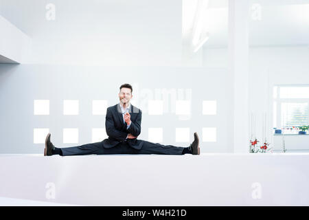 Smiling businessman faisant le grand écart à la réception desk in office Banque D'Images