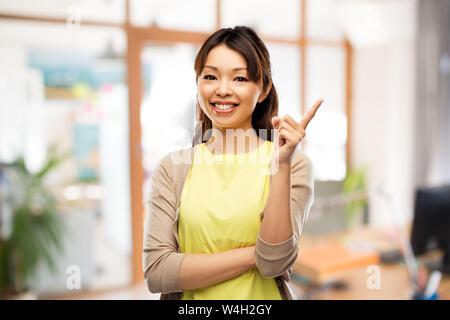 Happy asian woman pointing finger up at office Banque D'Images