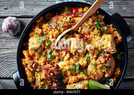 Arroz con pollo, une cuisine espagnole, le riz avec le poulet et les légumes dans une casserole sur une table rustique en bois, vue de dessus, flatlay, close-up Banque D'Images