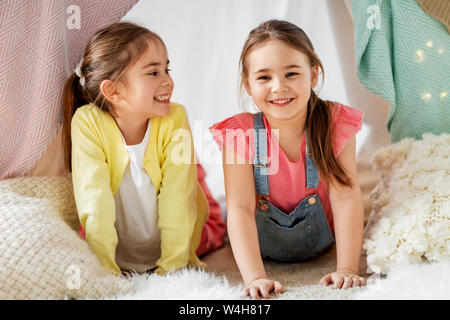 Happy girls lying in kids tente à l'accueil Banque D'Images